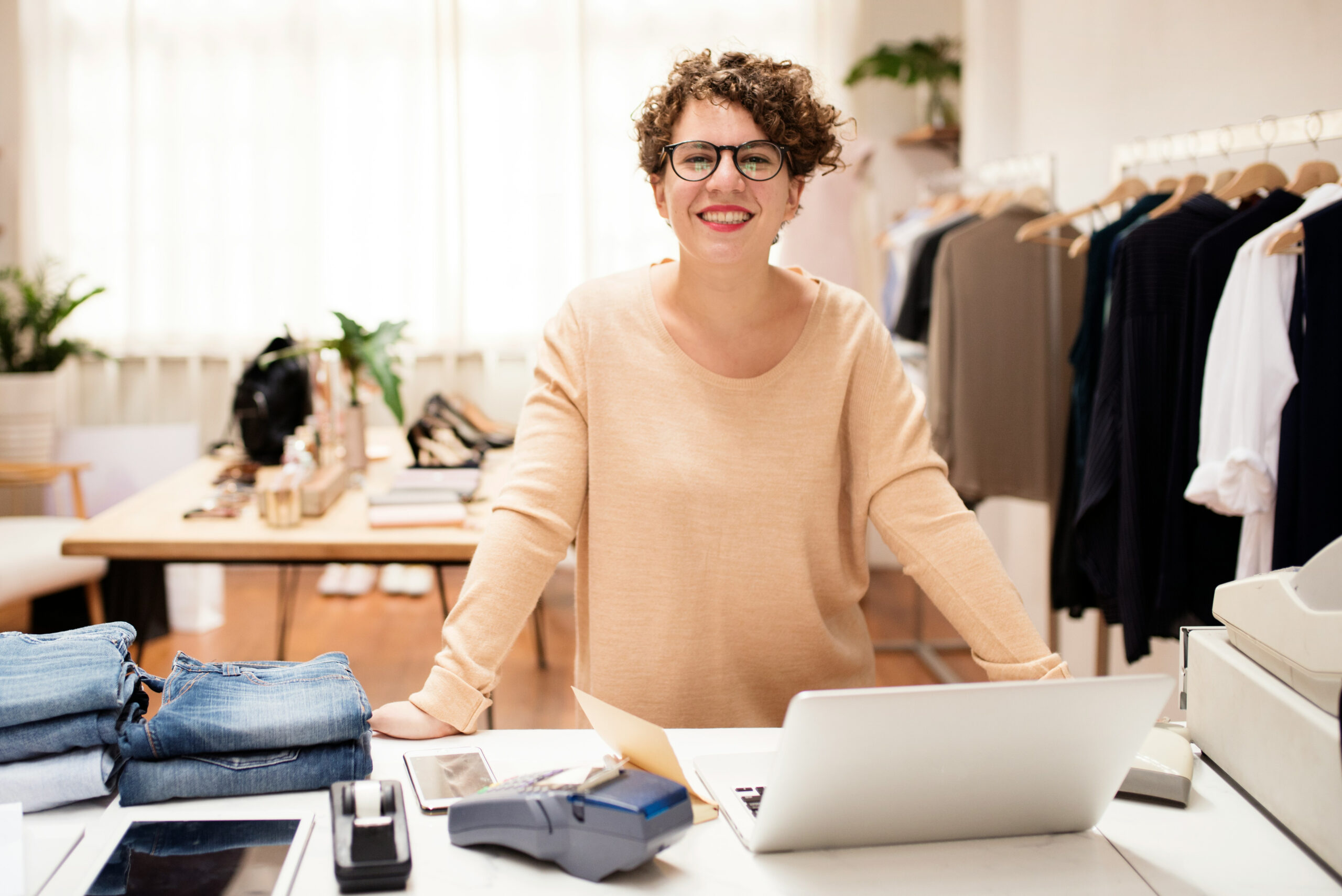 Retail shop owner smiling behind the counter of her store